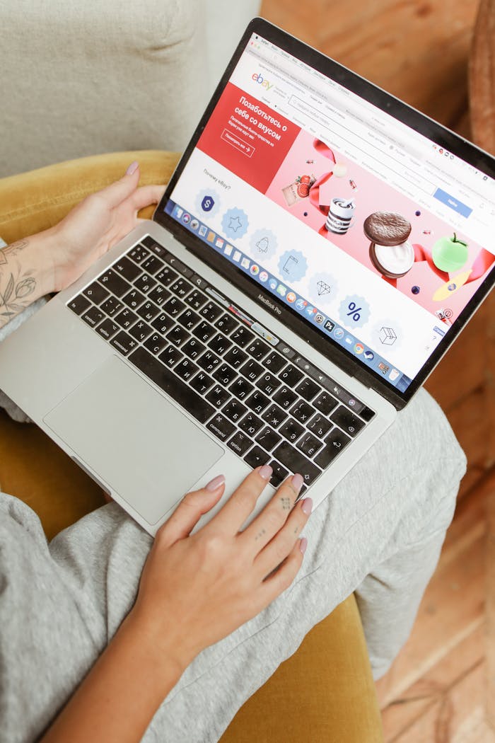 A woman sits comfortably indoors, browsing an online shopping website on her laptop.